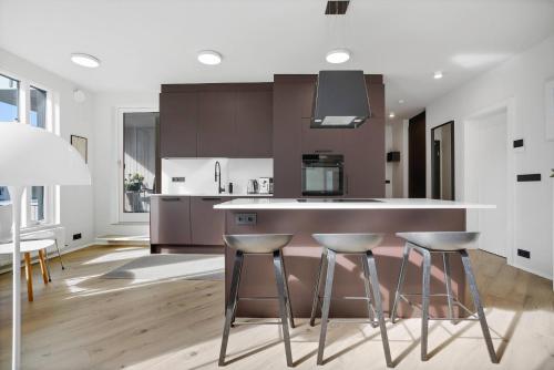 a kitchen with three bar stools and a counter at Spacious 2BR Apt with Balcony, Sauna and Free Parking in Reykjavík
