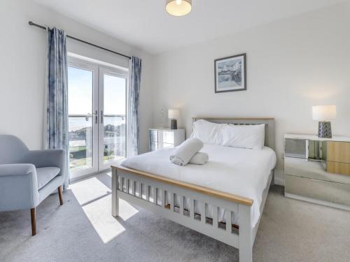ein Schlafzimmer mit einem Bett und einem Stuhl und einem Fenster in der Unterkunft Verbier Luxurious Seaside Retreat in Aberdyfi