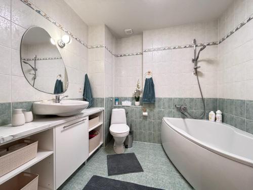 a bathroom with a tub and a sink and a toilet at Elegant and bright flat in a quiet area in Rīga