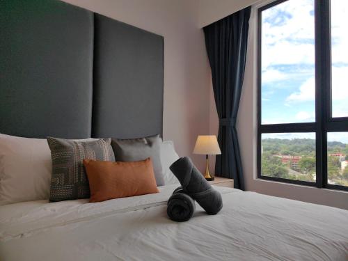 a bed with a stuffed animal on it with a window at Vetro11 Beside QEH1 by JUNE Homestay in Kota Kinabalu