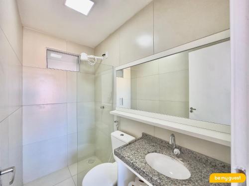 a bathroom with a toilet and a sink and a mirror at Beach Townhouses IV in Mangabeira
