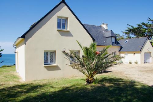 a house with a palm tree in front of it at Family home 7 people, direct beach, sea view in Locquirec