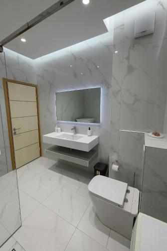 a white bathroom with a toilet and a sink at Zoo&Lake Appartment in Sauk
