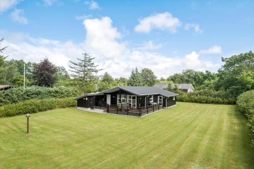 a black house in a field with a large yard at JB139-Fjerritslev-Kastanievej-13 in Fjerritslev