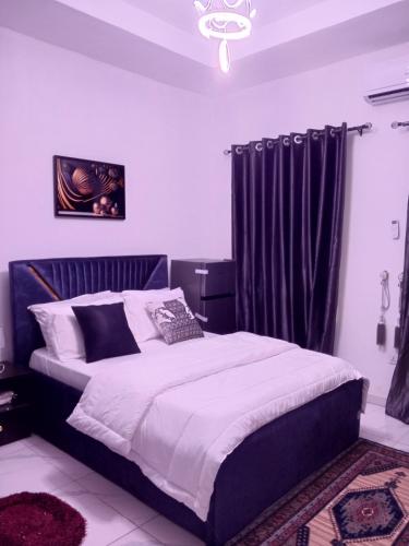 a bedroom with a large bed with black curtains at Peace Dew Apartments in Maiyegun