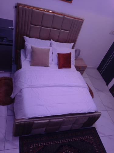 a bedroom with a large bed with white sheets and pillows at Peace Dew Apartments in Maiyegun