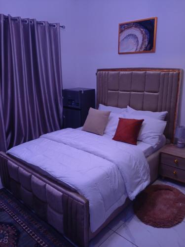 a bedroom with a large bed with white sheets and red pillows at Peace Dew Apartments in Maiyegun