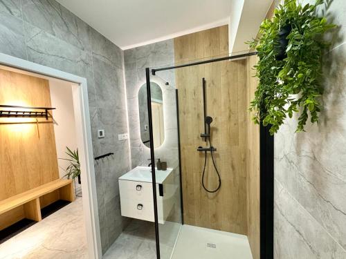 y baño con ducha, lavabo y plantas. en Apartament Uroczy w Szczyrku na stoku, en Szczyrk