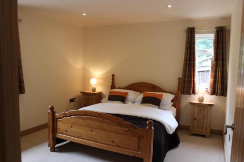 a bedroom with a wooden bed and two night stands at Loch Ness Highland Cottages with partial Loch View in Invermoriston