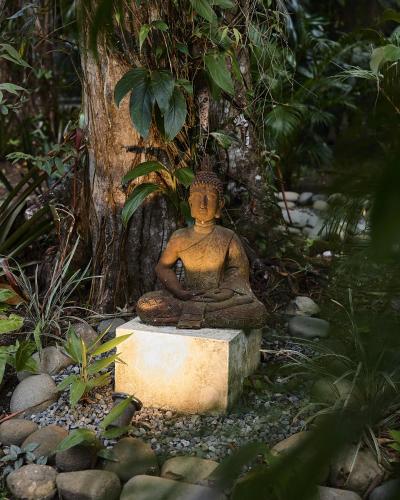 a statue sitting on a block in front of a tree at ZEN Villa in Punta Uva