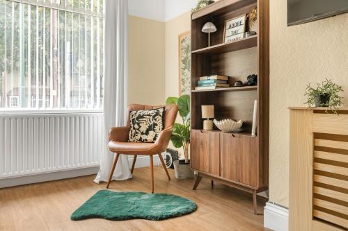 a living room with a chair and a book shelf at Rosewick Villa wt Office, Garden & Free Parking in Nottingham