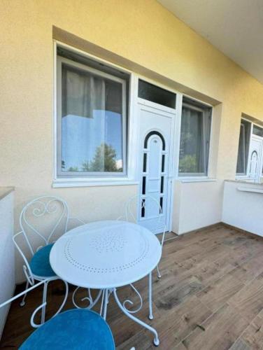 a white table and chairs in a room with windows at Apartman Elena Sunčani Breg Vrdnik in Vrdnik