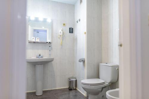 a white bathroom with a toilet and a sink at Hotel Alda Ribeira in Ribeira