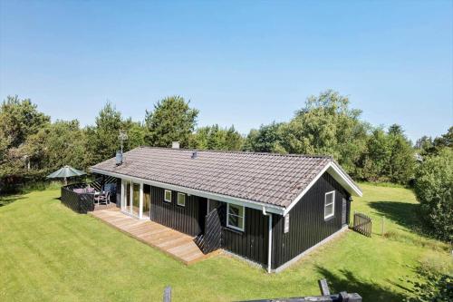 a black house with a deck on a yard at JB293-Fjerritslev-Tyttebaerstien-24 in Torup Strand