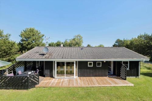 a small black house with a wooden deck at JB293-Fjerritslev-Tyttebaerstien-24 in Torup Strand