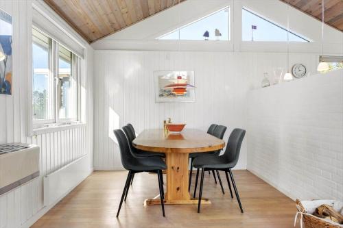 a dining room with a wooden table and black chairs at JB219-Fjerritslev-Tyttebaerstien-4 in Torup Strand