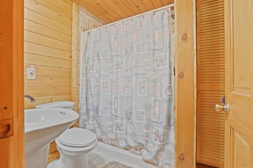 a bathroom with a toilet and a shower curtain at 10-Acre Cabin, Sauna, Hot Tub, Game Rm, Stargazing Dome, EV, BBQ in Logan