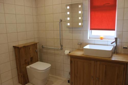 ein Badezimmer mit Toilette und Waschbecken und einem Fenster in der Unterkunft Loch Ness Highland Cottages with partial Loch View in Invermoriston