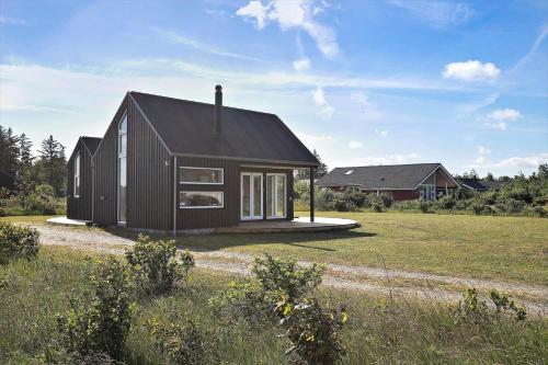 a small black house sitting on top of a field at JB176-Brovst-Kronvildtvej-152 in Tranum