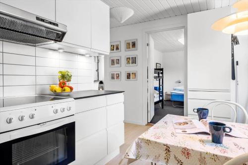a kitchen with white cabinets and a table with a bowl of fruit at JB246-Brovst-Graevlingevej-13 in Tranum
