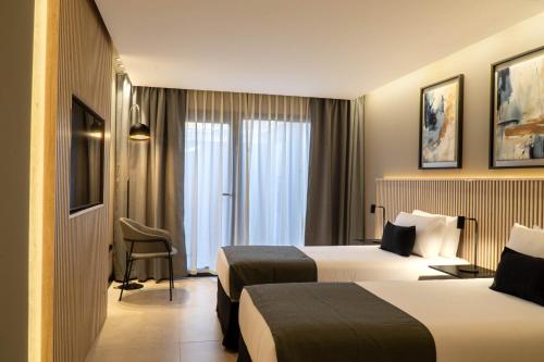 a hotel room with two beds and a chair at Mabra Suites in El Calafate