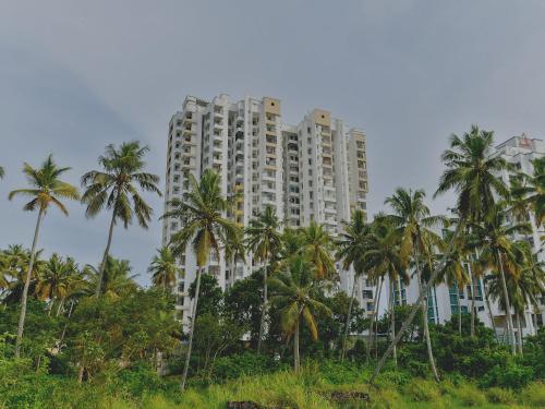 a tall building with palm trees in front of it at Super Hotel O Tyche Stays in Trivandrum