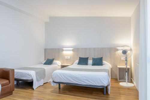 a hotel room with two beds and a chair at Hotel Alda Ribeira in Ribeira