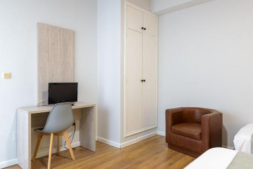 a bedroom with a desk with a television and a chair at Hotel Alda Ribeira in Ribeira