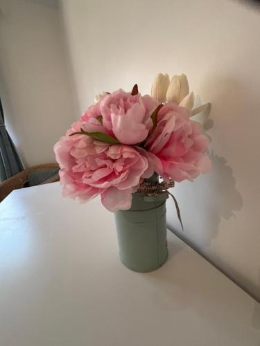 a green vase filled with pink flowers on a table at Killaloe Lakeside Holiday Home 2Bedroom in Killaloe