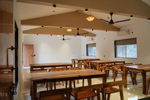 a dining room with wooden tables and chairs at Vrindaa- The Bliss Retreat in Karjat