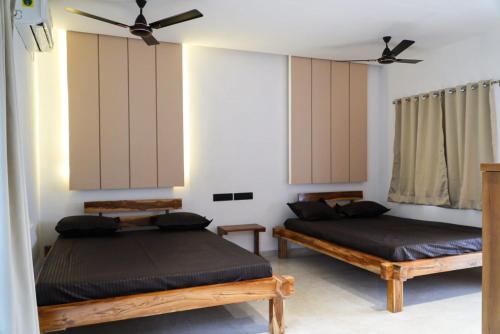 a bedroom with two beds and a ceiling fan at Vrindaa- The Bliss Retreat in Karjat