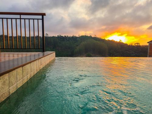 una gran masa de agua con la puesta de sol en el fondo en Gran Chalé, en Santa Teresa