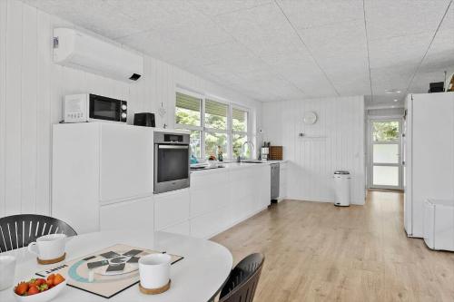 a white kitchen with a table and a refrigerator at JB318-Fjerritslev-Fiskerstien-10 in Torup Strand