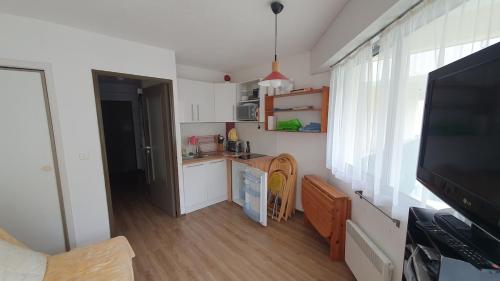 オー・ボンヌにあるStudio à Gourette pour 4 personnes avec balcon, casier à skis et vue montagneのテレビ、テーブル付きのキッチンが備わります。