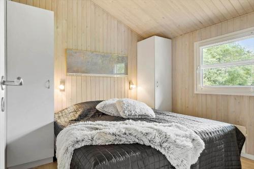 a bedroom with a bed with a blanket and a window at JB716-Fjerritslev-Tyttebaerstien-16 in Torup Strand