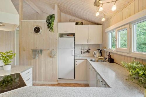 a kitchen with white cabinets and a white refrigerator at JB716-Fjerritslev-Tyttebaerstien-16 in Torup Strand