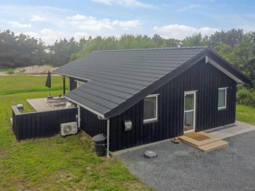 a black tiny house with a porch and a deck at Holiday Home Holke - 600m from the sea by Interhome in Hirtshals