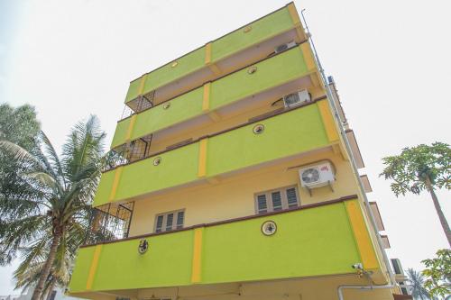 Un edificio alto amarillo y verde con palmeras. en Hotel O Surya Residency, en Muthugadahalli