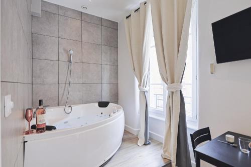 a white bath tub in a bathroom with a window at LES BULLES DE MONA - Zen - Spa - Clim in Lyon