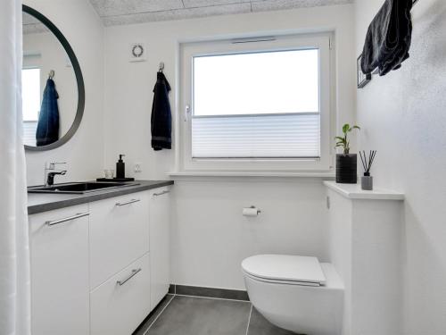 a white bathroom with a toilet and a window at Holiday Home Antina - 400m from the sea by Interhome in Hjørring