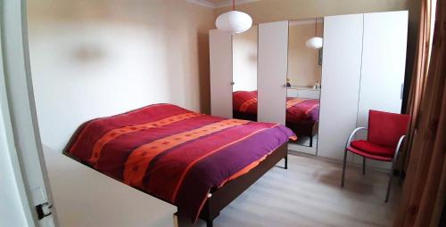 Un dormitorio con una cama, un espejo y una silla. en Miss Cato, en Ostende