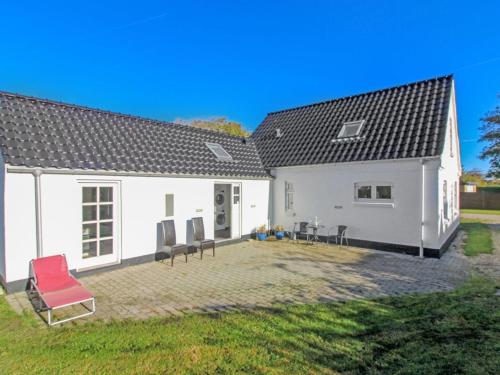 a white house with red chairs and a yard at Holiday Home Iara - 6km from the sea by Interhome in Bindslev