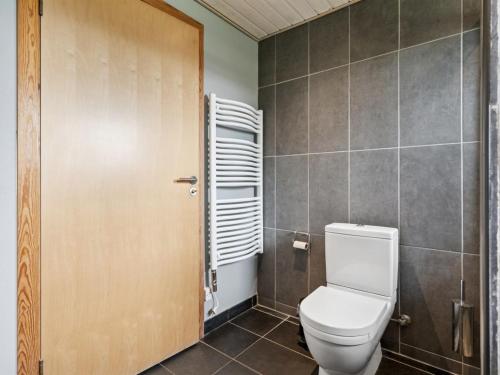 a bathroom with a toilet and a wooden door at Holiday Home Harka - 100m to the inlet by Interhome in Roskilde