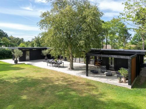 an outdoor patio with a tree and a house at Holiday Home Hævnir - 1km from the sea by Interhome in Vejby