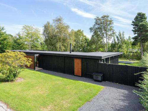 a black house with a black roof and a yard at Holiday Home Hævnir - 1km from the sea by Interhome in Vejby