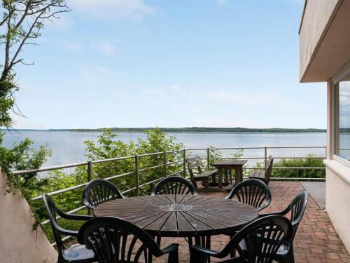 einen Tisch und Stühle auf einer Terrasse mit Blick auf das Wasser in der Unterkunft Holiday Home Grumme - 30m to the fjord by Interhome in Ølsted