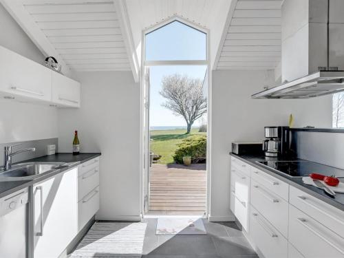 a kitchen with white cabinets and a large window at Holiday Home Trajko - 100m from the sea by Interhome in Hou