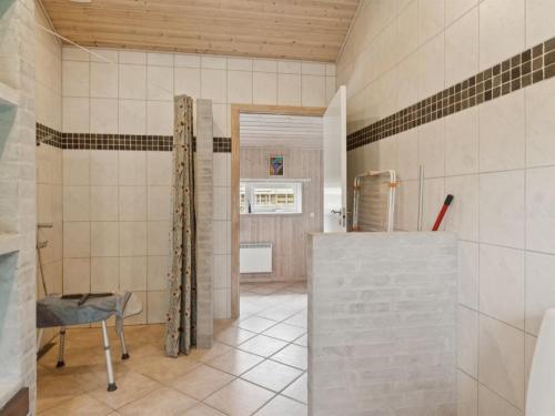 a bathroom with a shower and a tile wall at Holiday Home Brunman - 10m to the fjord by Interhome in Grevinge