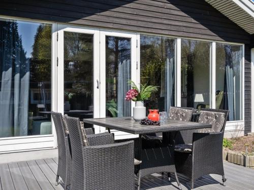 a dining table and chairs on a porch with glass doors at Holiday Home Øllegaard - 1km from the sea by Interhome in Dronningmølle