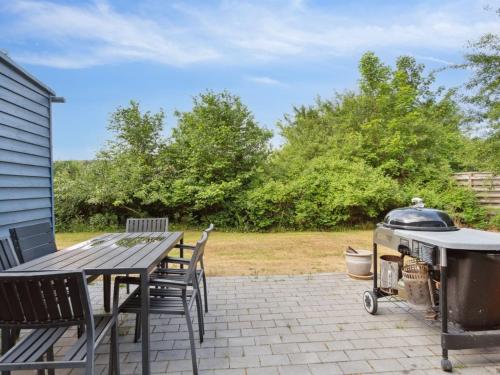 a grill on a patio with a table and chairs at Holiday Home Hannelore - 700m from the sea by Interhome in Nykøbing Sjælland